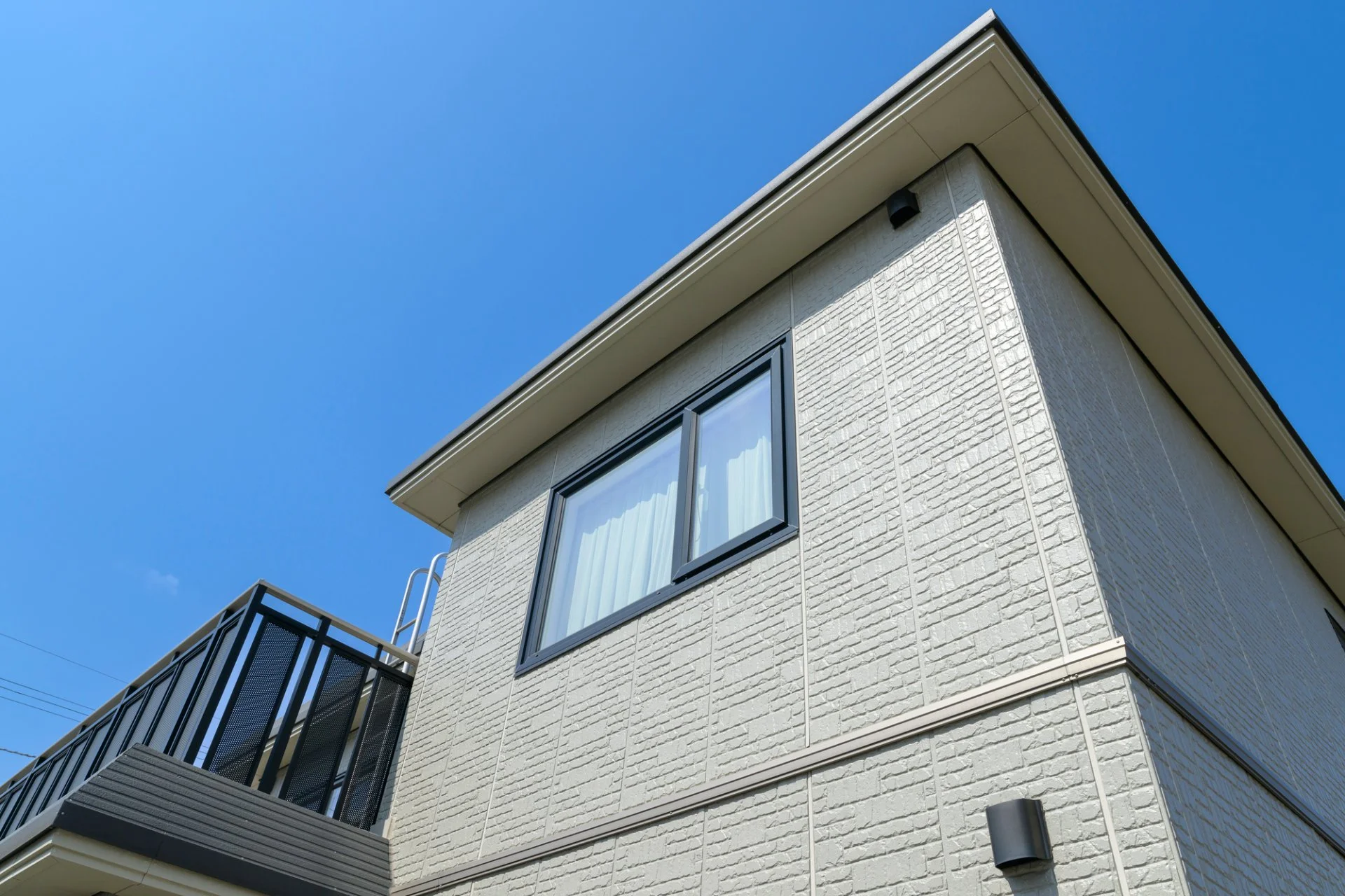 外壁のひび割れ補修後、塗装の色合わせまで整った二階建て住宅の近景